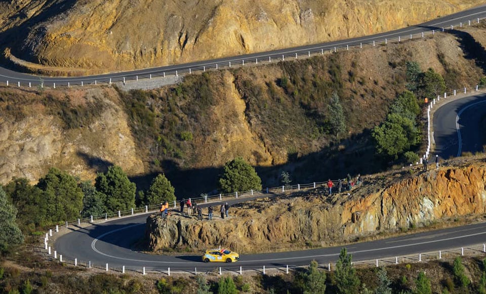 Yellow car drives winding road.
