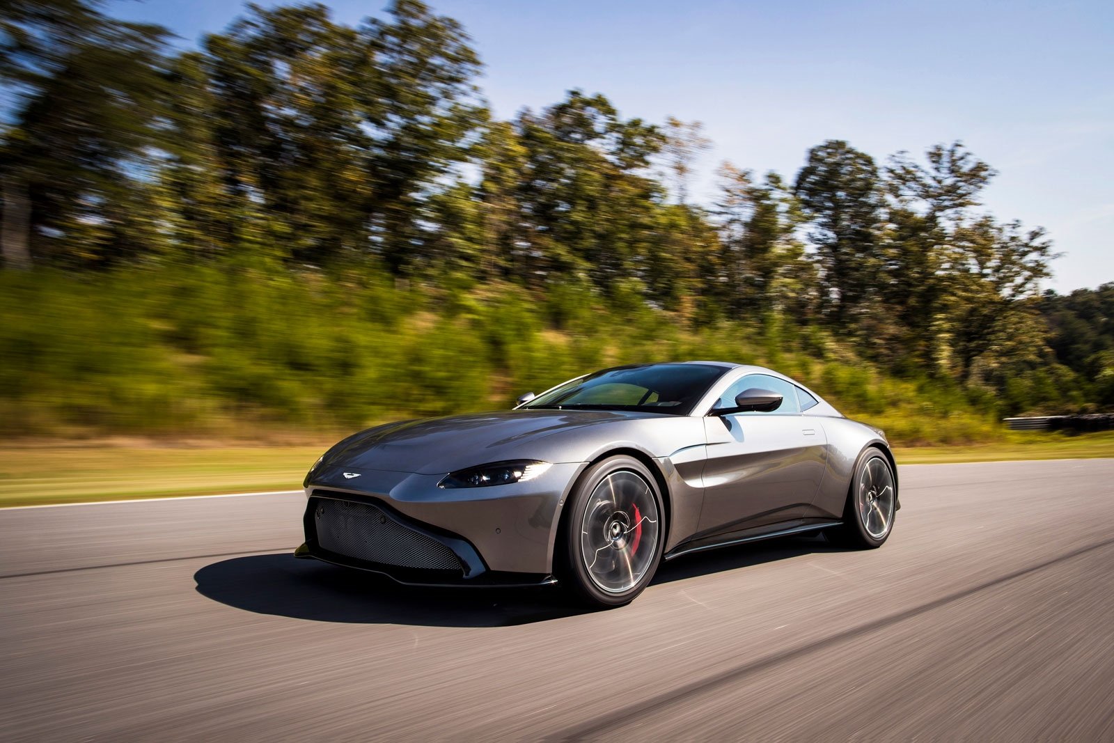 Gray sports car glides through scenic landscape.