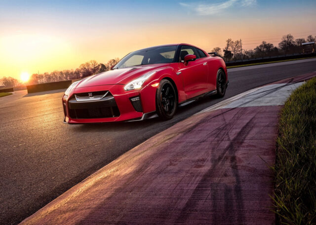 Red Nissan GT-R on racetrack at sunset.