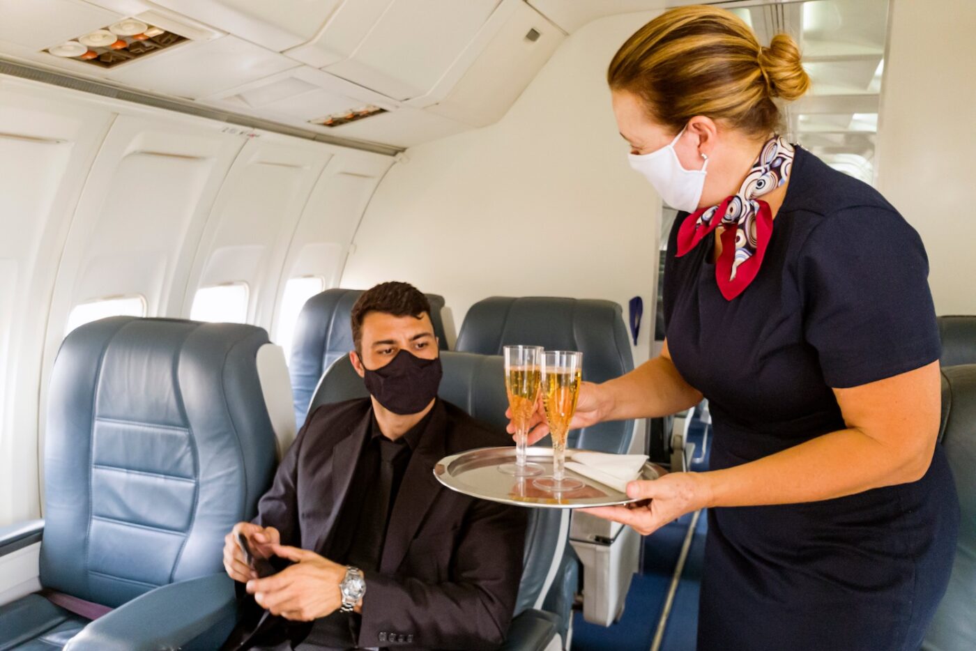 A man being served champagne in business class.