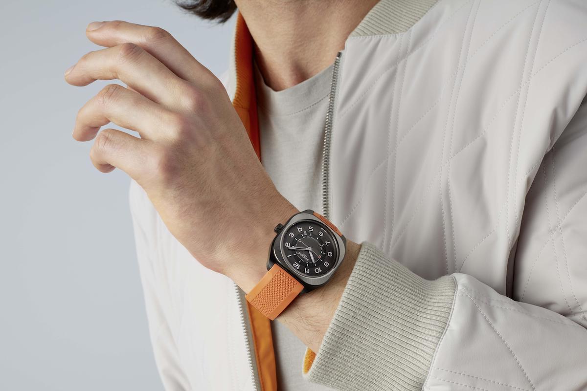 Person shows Bulgari watch with orange strap.
