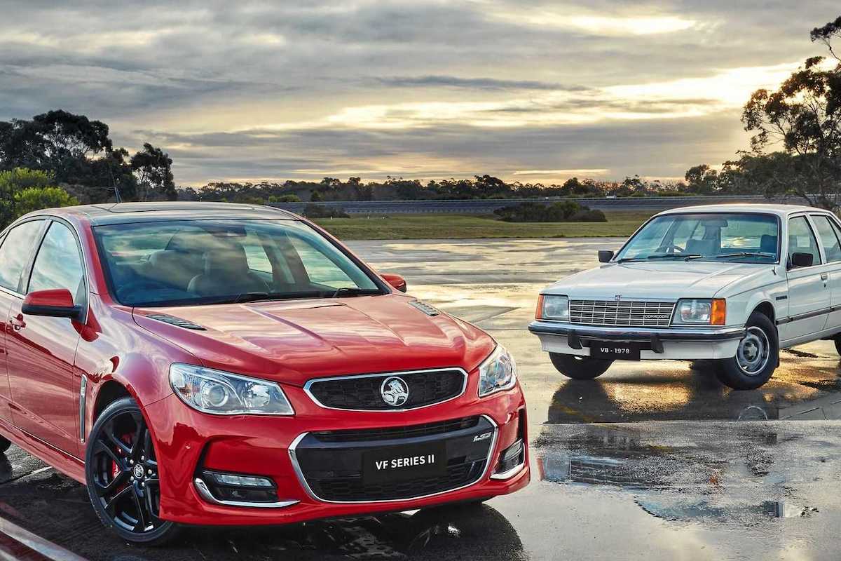Red Holden sedan beside vintage blue Holden.