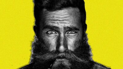 A serious bearded man on yellow background.