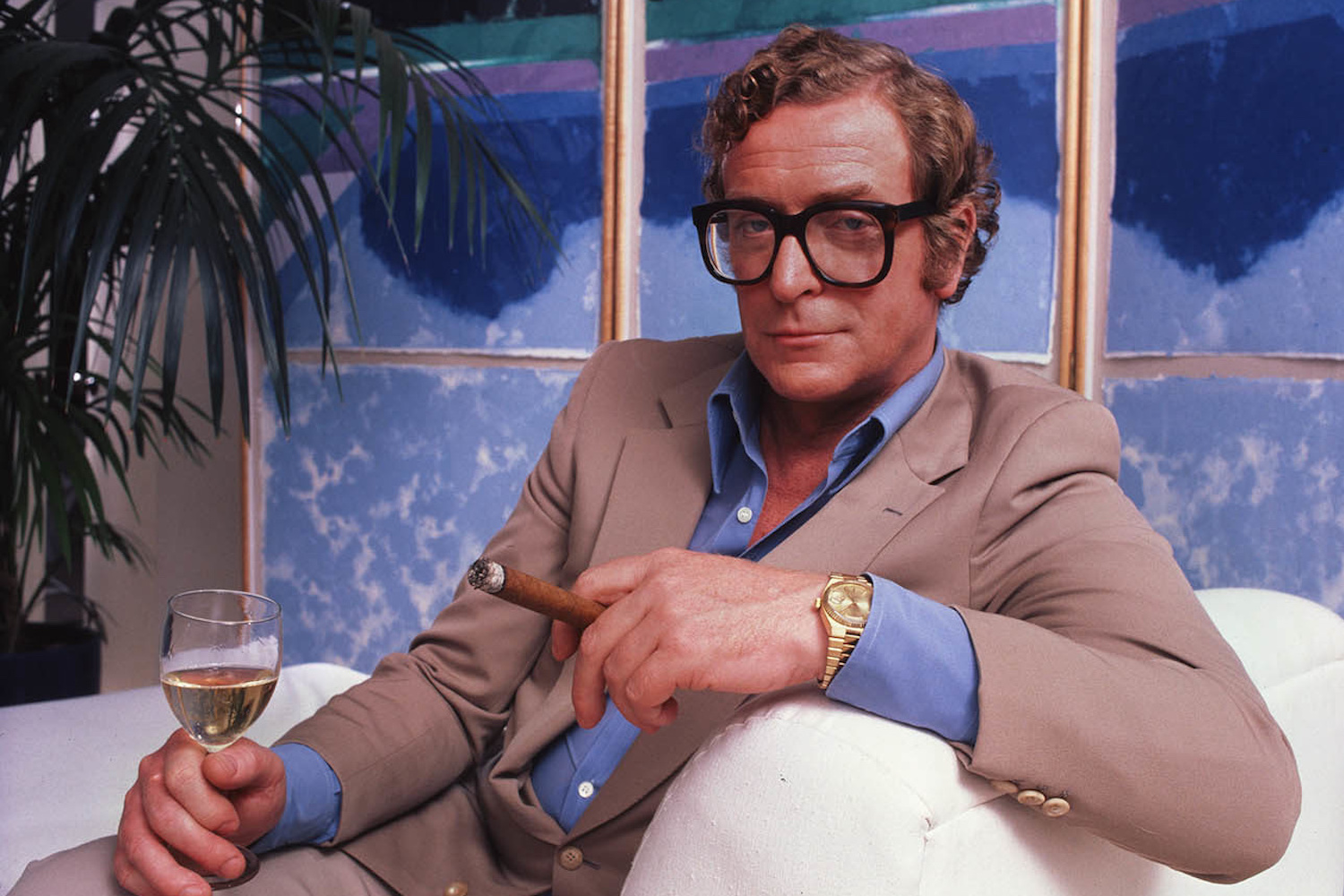 Person in beige suit checks Rolex watch.