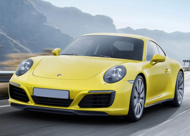 Yellow Porsche 911 Carrera on coastal road.