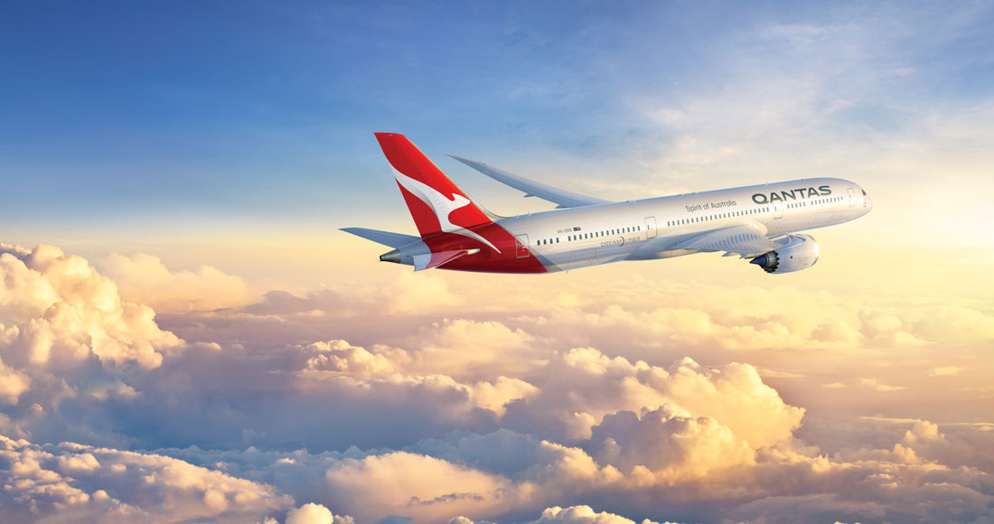 Qantas airplane flies during sunrise.