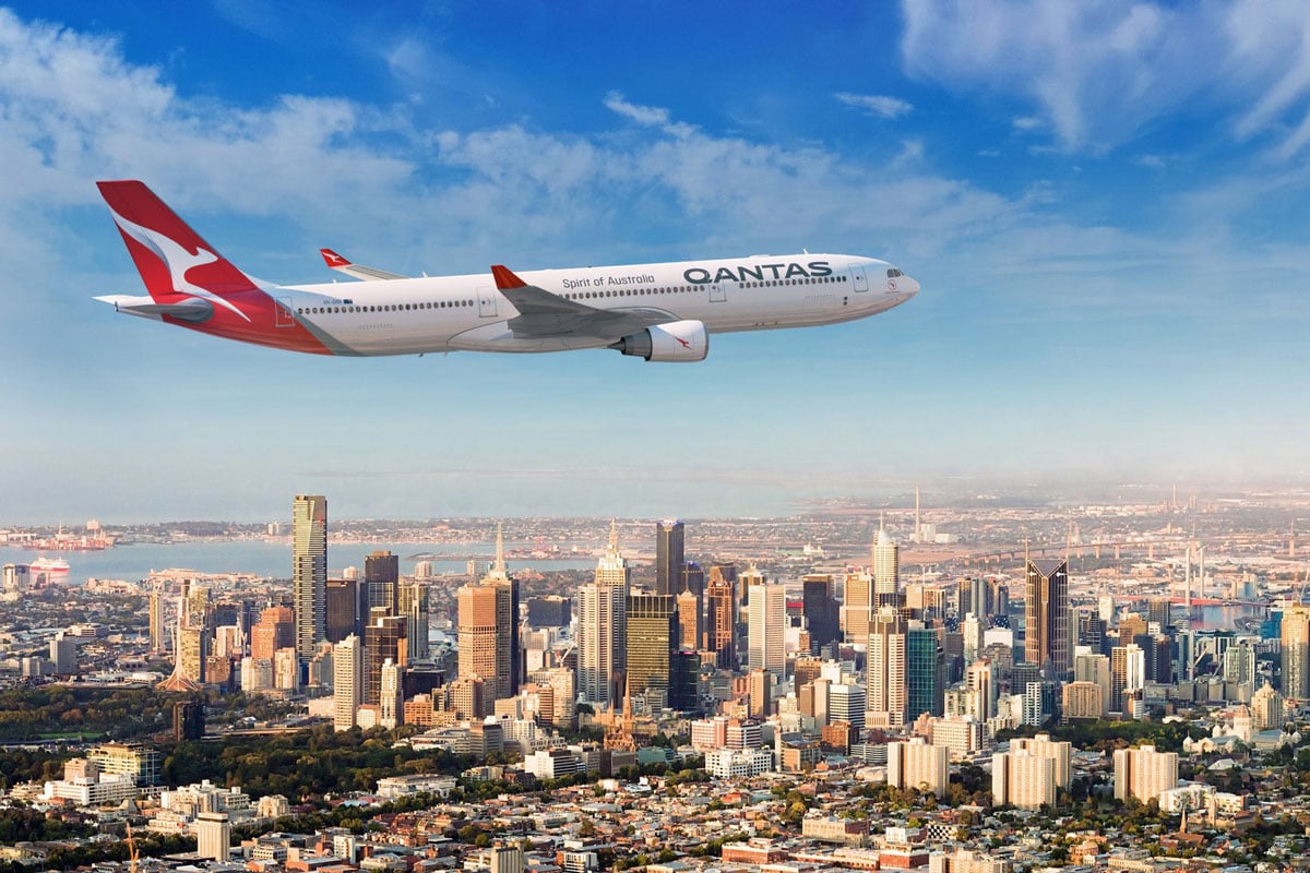 Qantas plane over modern cityscape.