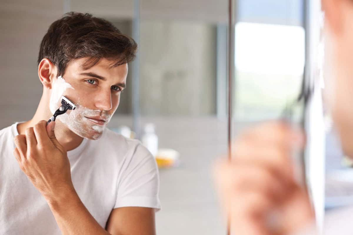 Man shaves using cream, razor.