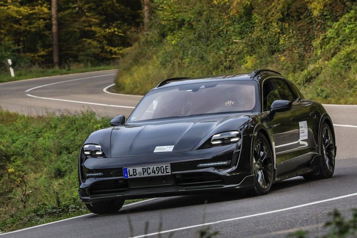 Porsche Taycan Cross Turismo driving through lush greenery.