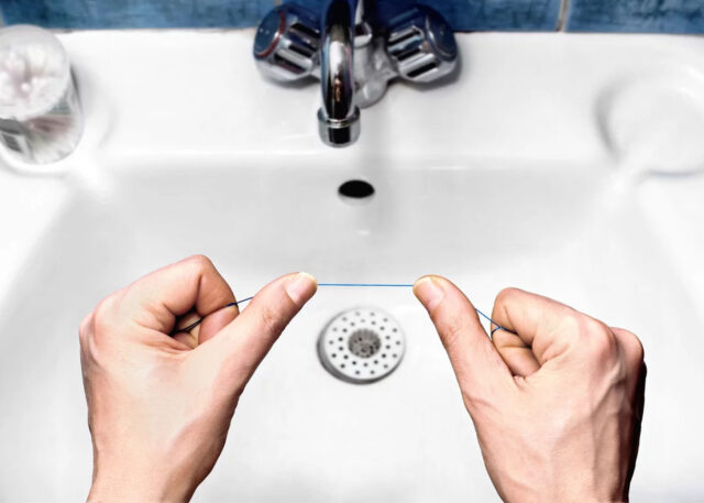 Holding dental floss over a shiny sink.