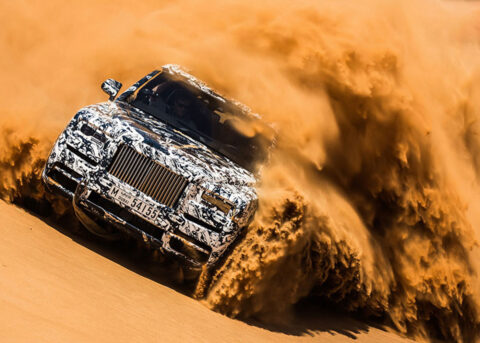 Rolls Royce Cullinan speeds through desert sand.